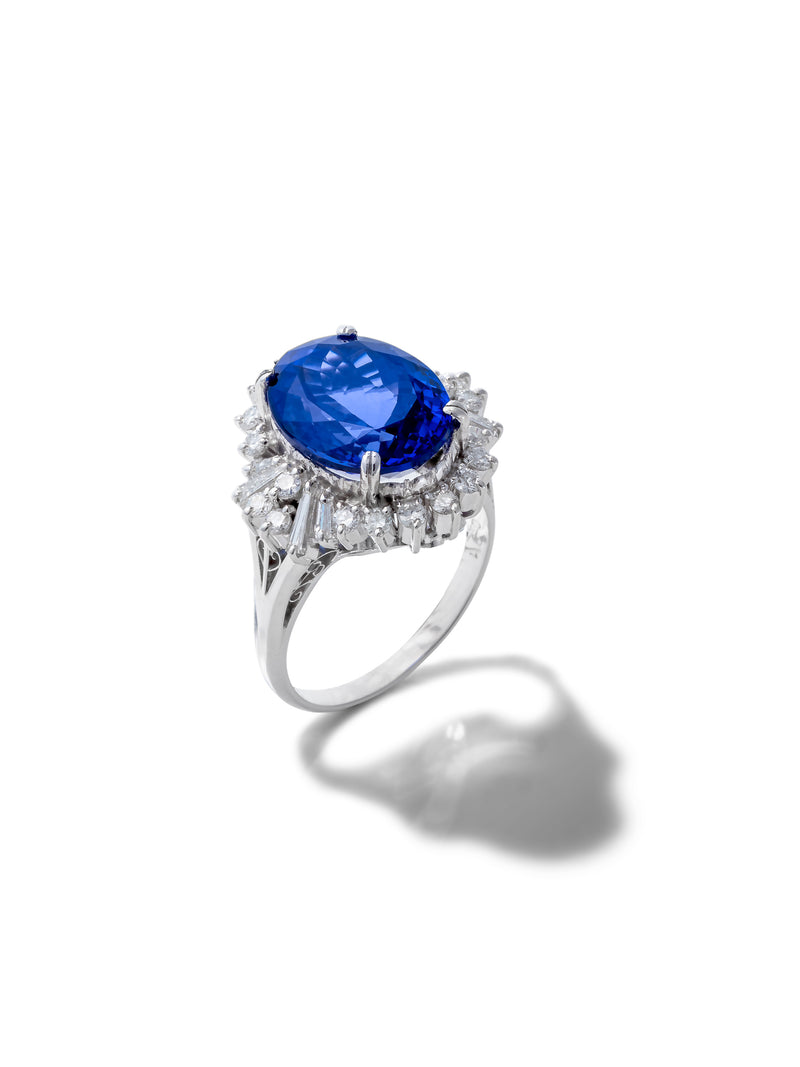 A silver ring featuring a large oval-cut deep blue sapphire center stone surrounded by a halo of small clear diamonds, set against a plain white background with a soft shadow.